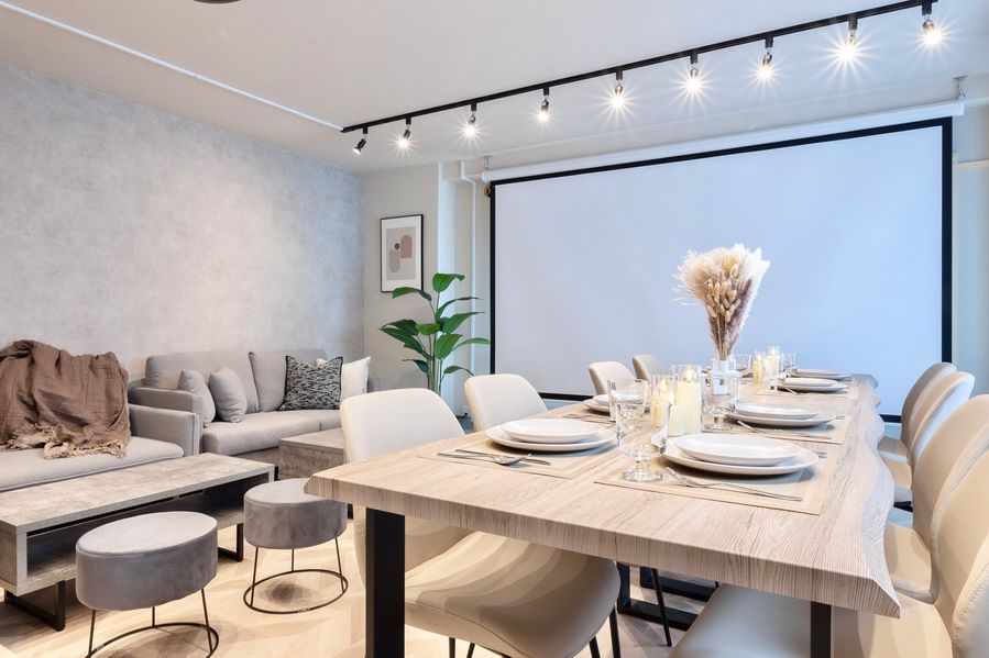 テーブルにキャンドルとパンパスグラスを飾ったパーティーセッティング。スクリーンを背景に、ソファとダイニングが一体になった空間全体が見渡せる。