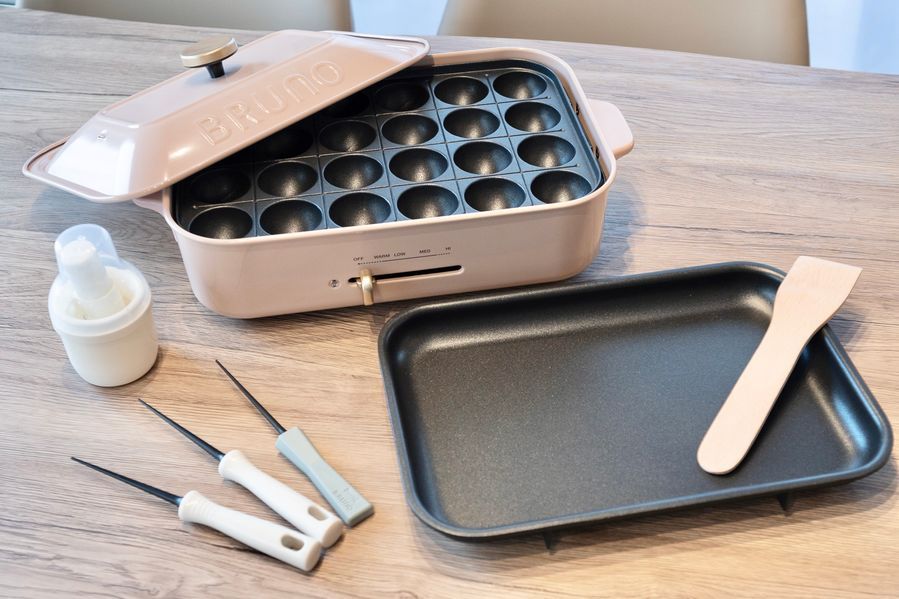 ピンクベージュのBRUNOコンパクトホットプレート。たこ焼きプレートと平面プレートが並び、専用ピックとオイルボトルも付属している。