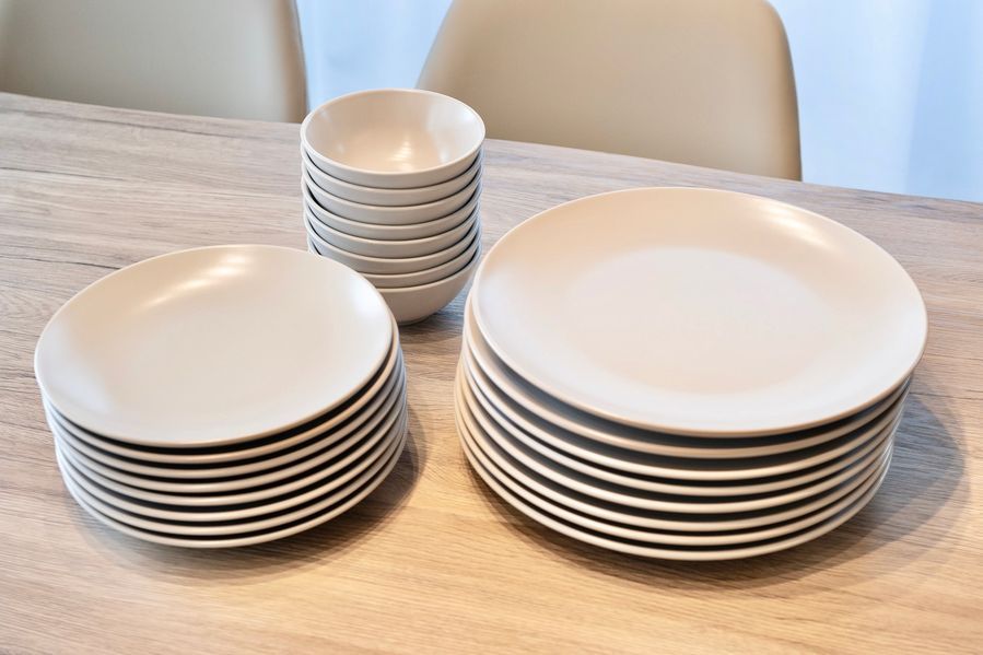 マットな質感のベージュの食器が3種類。大皿、中皿、ボウルがきれいに重ねられている。