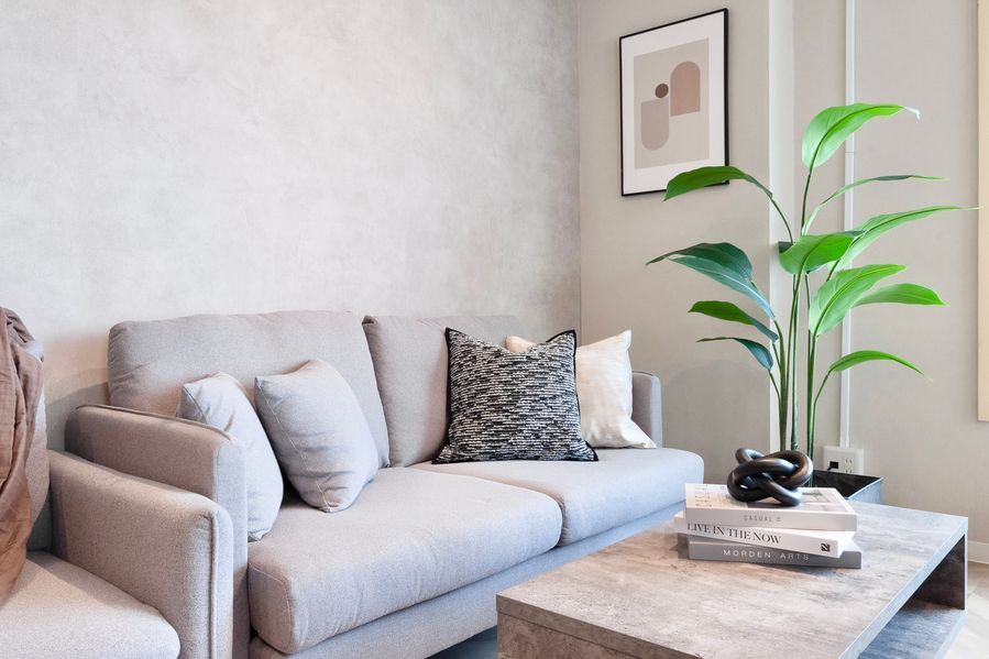 ソファのクッションとアクセントウォールのアップ。アートプリントと観葉植物がモダンな空気感を演出している。